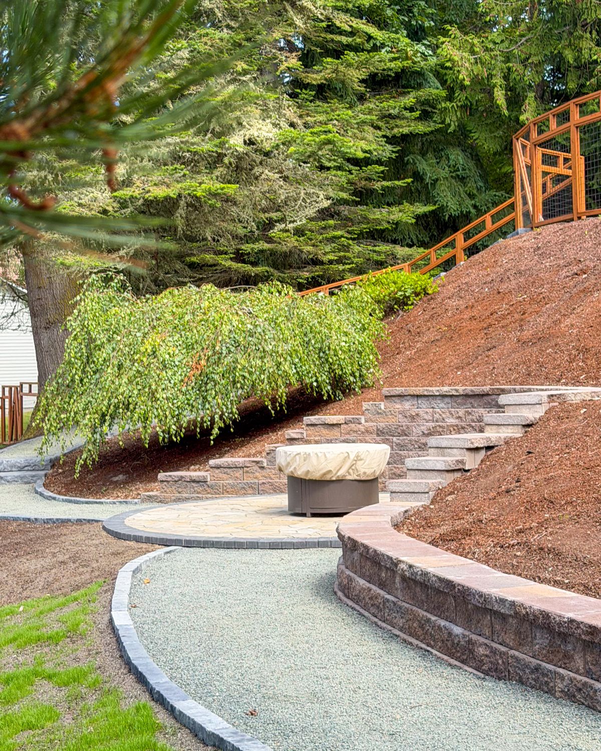Fire pit patio with block steps and curved retaining walls on a hillside