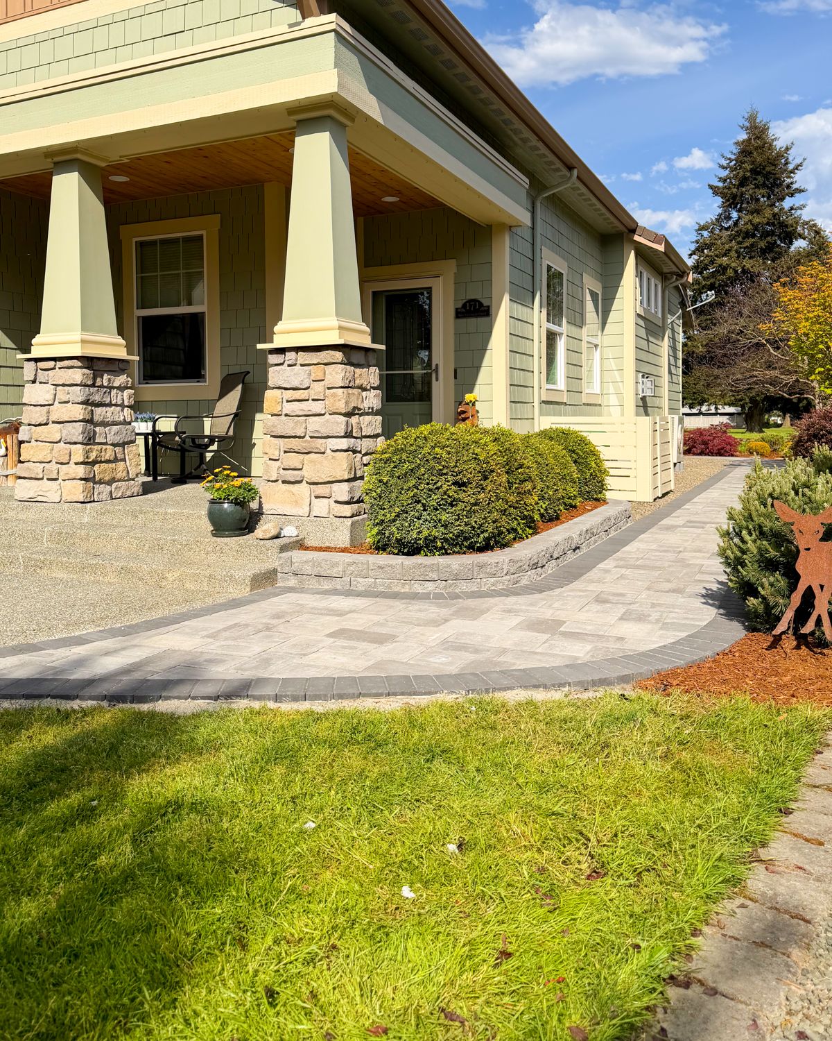 Light gray paver front walkway with a charcoal border along a craftsman porch