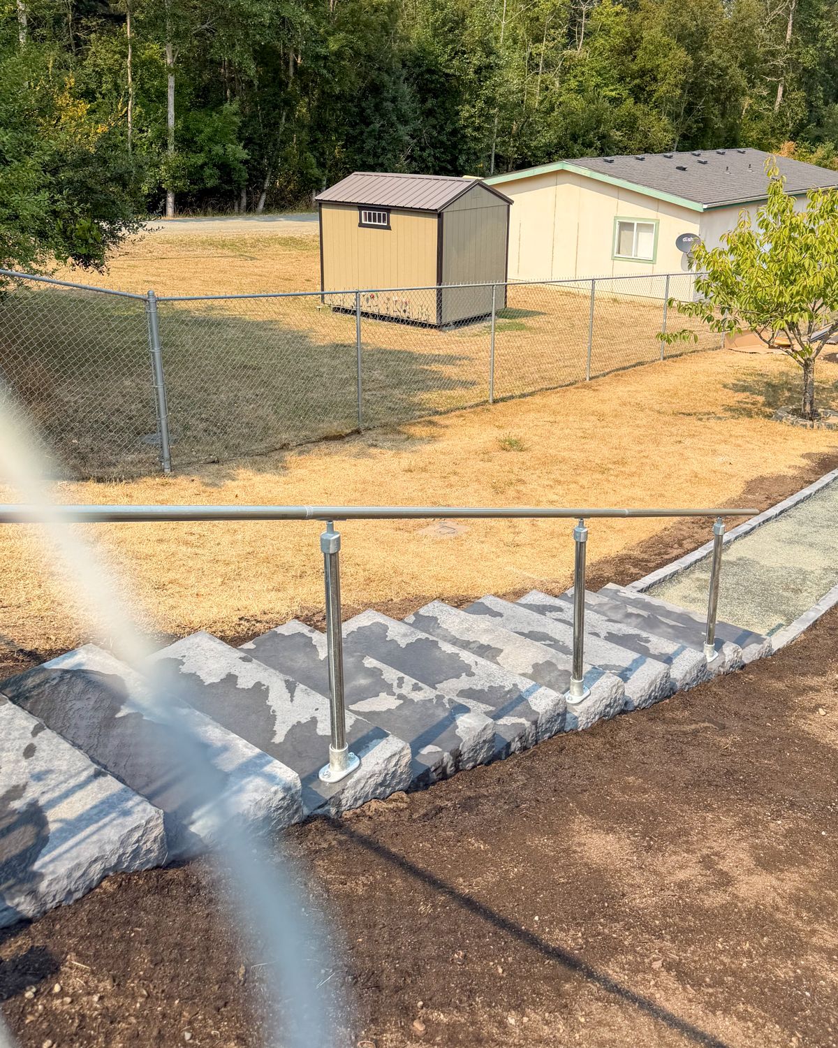 Large stone slab steps with a metal handrail on a slope